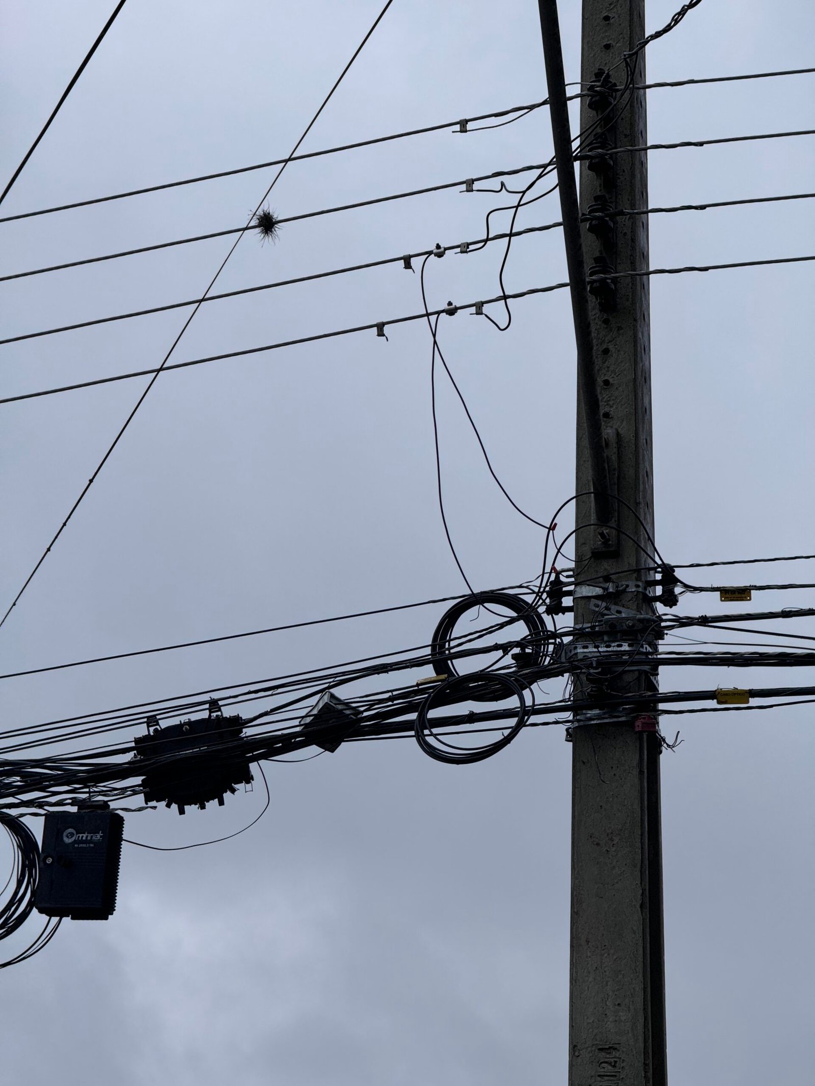 Fotos de um poste com diversos cabos de telecomunicações